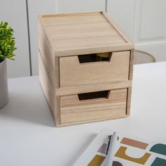 a wooden box sitting on top of a white table next to a potted plant