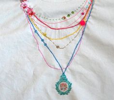 multicolored beaded necklaces are displayed on a white shirt