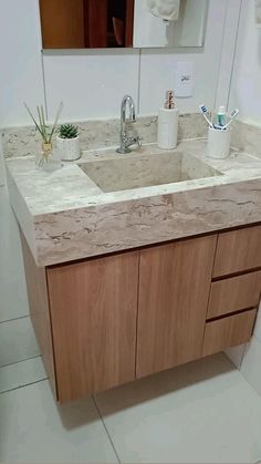 a bathroom sink sitting under a mirror next to a wooden cabinet