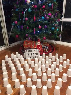 a christmas tree is decorated with white cups and the words find the hidden treat on it