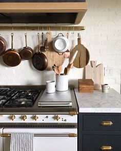 pots and pans are hanging on the wall above an oven