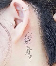 a woman's behind the ear has a bird tattoo on it