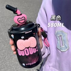 a person holding a black cup with pink decorations on it and a purple hoodie