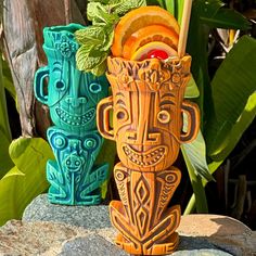 two tiki style vases sitting on top of a rock