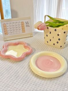 a table topped with plates and vases filled with tulips next to a calendar