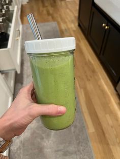 a person holding a green smoothie with a straw in it's hand and looking at the camera