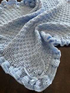 a blue crocheted blanket laying on top of a wooden floor