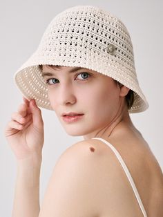 a woman wearing a white crochet hat with buttons on the brim and shoulder