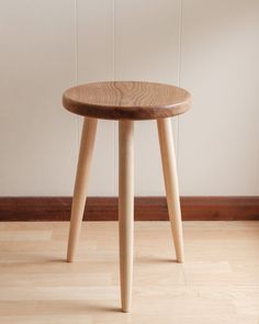 a small wooden table sitting on top of a hard wood floor next to a white wall