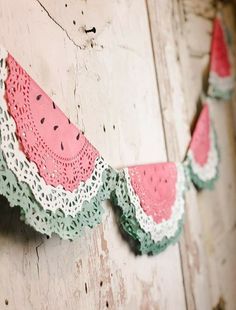 a watermelon bunting hanging on the side of a wooden wall with crocheted lace