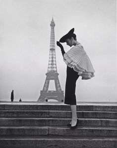 a black and white photo of a woman in front of the eiffel tower