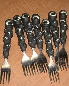six forks with black and white eyes are lined up next to each other on a wooden surface