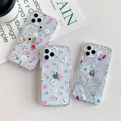 three iphone cases with flowers on them sitting next to a coffee cup and magazine holder