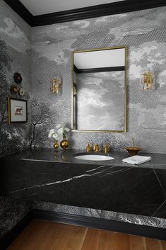 a bathroom with marble counter tops and gold faucets on the sinks, along with a large mirror