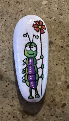 a painted rock with a bug holding a flower