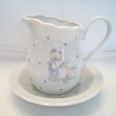 a white porcelain pitcher and saucer on a plate with a small bowl underneath it