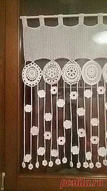 the window is decorated with crocheted doily and white flowers on it's side