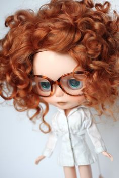 a close up of a doll with glasses on it's head and curly hair