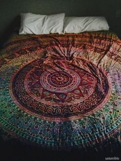 a bed covered in a multicolored bedspread with an intricate design on it