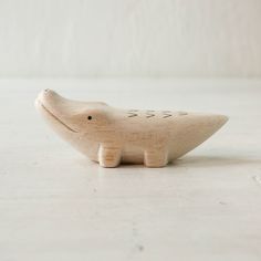 a wooden toy shaped like a fish on a white table with a wall in the background