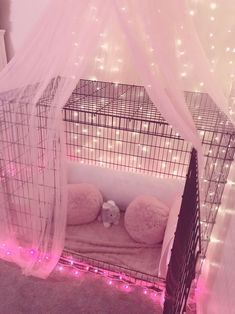 a dog cage with lights around it and a teddy bear in the bed on top