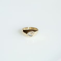 a gold ring with a white diamond on the top and bottom, sitting on a white surface