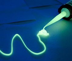 a tube of fluorescent ink sitting on top of a blue surface next to a white cord