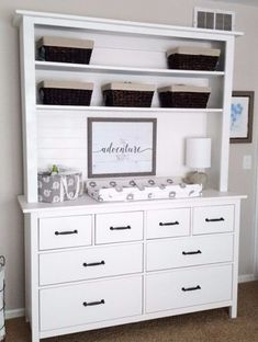 a baby's nursery room with white furniture and baskets on the shelves above it