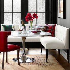 a dining room table with red chairs next to a white bench and window in the background