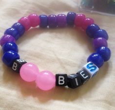 a close up of a beaded bracelet on a bed with beads that spell out the word bleu