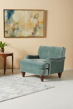 a living room with two chairs and a rug in front of a painting on the wall