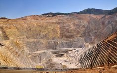 a large open pit in the middle of a mountain range with mountains in the background
