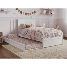 a white bed sitting on top of a wooden floor next to a rug and window