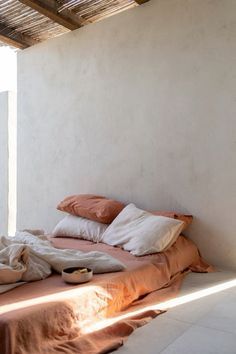 an unmade bed sitting under a wooden roof