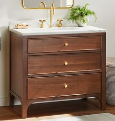 a bathroom vanity with two drawers and a gold framed mirror on the wall above it