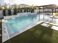 an empty swimming pool in the middle of a backyard with artificial grass on the ground