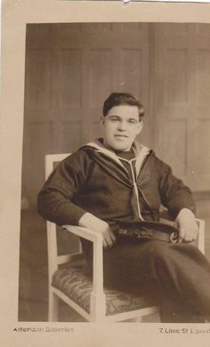 an old black and white photo of a man in a sailor's outfit sitting on a chair