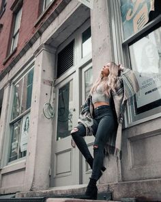 a woman leaning up against the side of a building