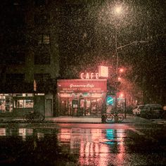 a rainy night in the city with cars parked on the street