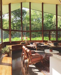 a living room filled with lots of windows and furniture next to plants on the wall