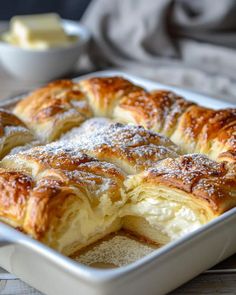 a pastry in a baking dish with powdered sugar on top