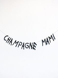 the words champagne mam are hanging from a string on a white background with black letters