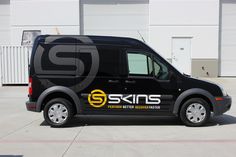 a black van parked in front of a building with the skins logo on it's side