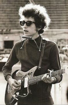a woman wearing sunglasses and holding an electric guitar