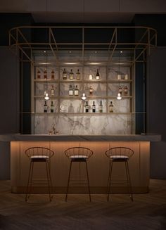 two bar stools in front of a marble counter with bottles on the back wall