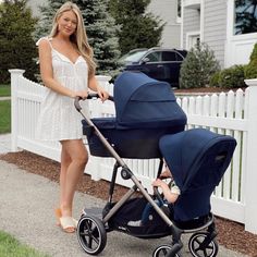 a woman standing next to a baby in a stroller