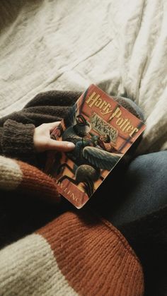a person laying in bed with a harry potter book on their lap, reading it