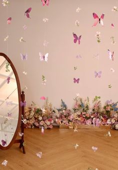 a mirror sitting on top of a wooden floor next to a wall covered in butterflies