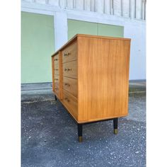 a wooden chest of drawers sitting on top of cement ground next to a garage door