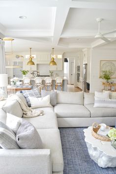 a living room filled with white furniture and lots of pillows on top of it's couches